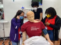Michelle Vu, a rising senior at Collins Hill High School; Sylvester Lee, a rising senior at Peachtree Ridge High School: and Inara Tate, a rising sophomore at Lakeside High School; examine their “patient’s” vital signs. Photo provided.